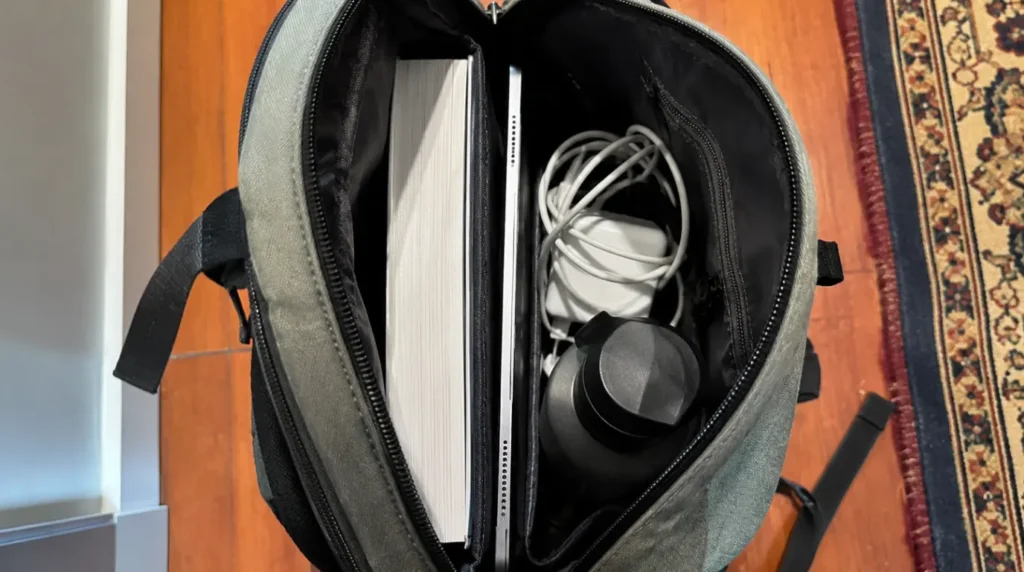 iPad wedged tightly between textbook and charger inside an overpacked backpack