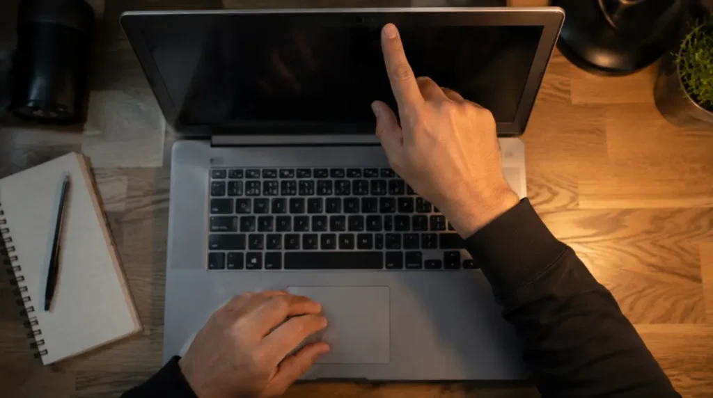 Hands checking a laptop's webcam bezel while troubleshooting a frozen camera during a call